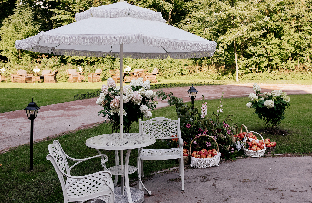 Зонтик и кресла в парке декорированные живыми цветами и яблоками