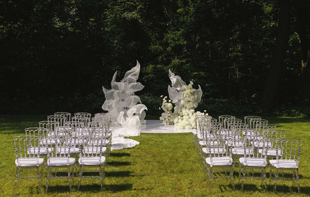 Белоснежный свадебюный подиум с таким же белым декором и зелень сада виллы