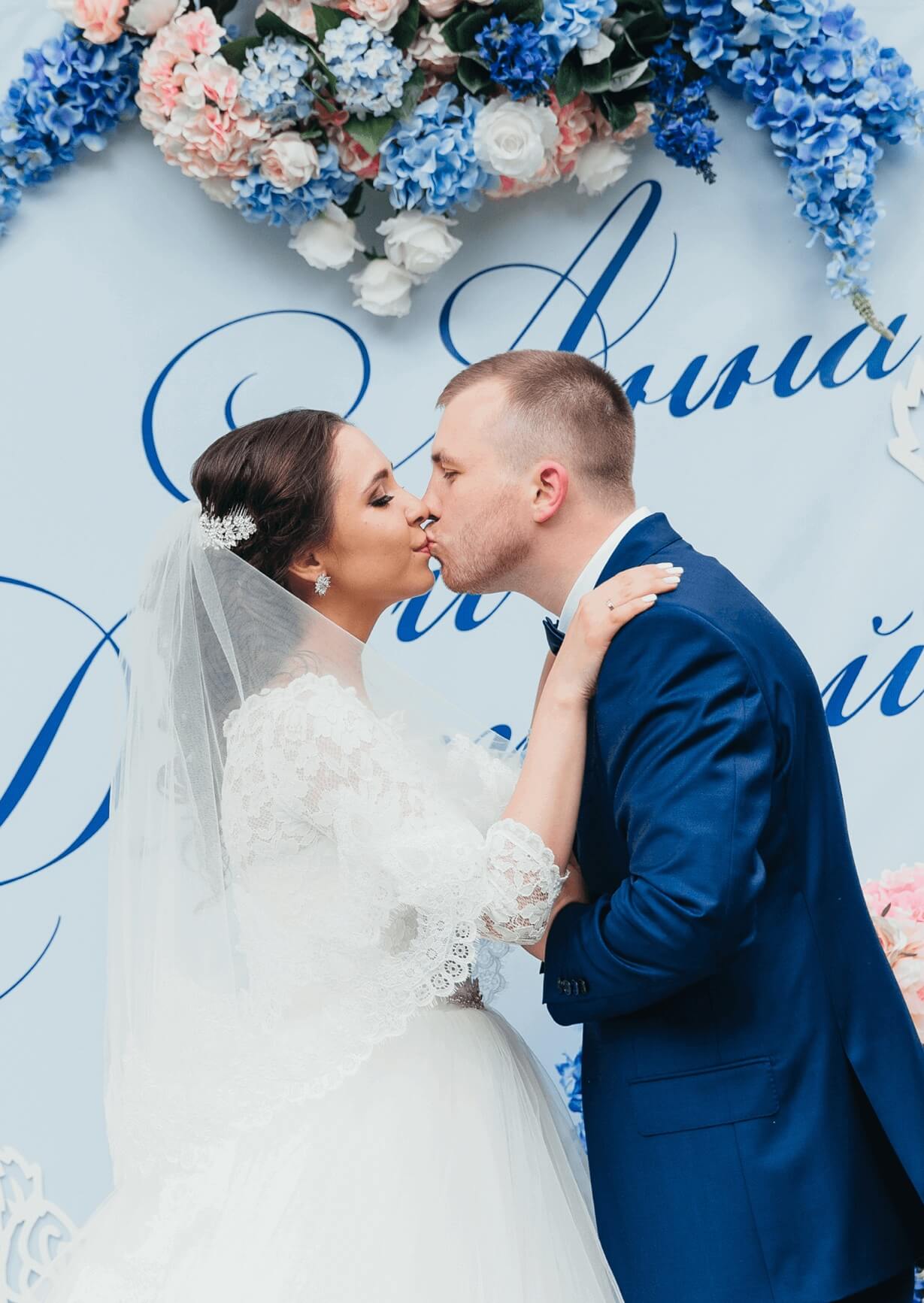 Поцелуй жениха и невесты на фоне живых цветов