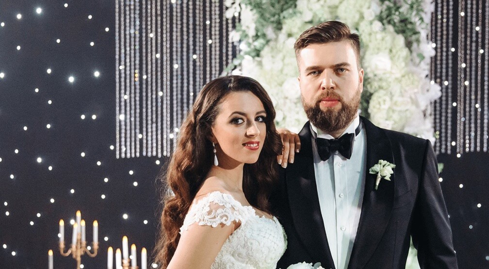 Александр и Александра крупным планом в свадебных декорациях