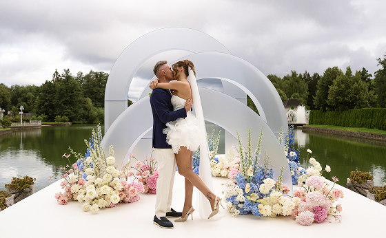 Поцелуй молодоженов на фоне водоема и парка